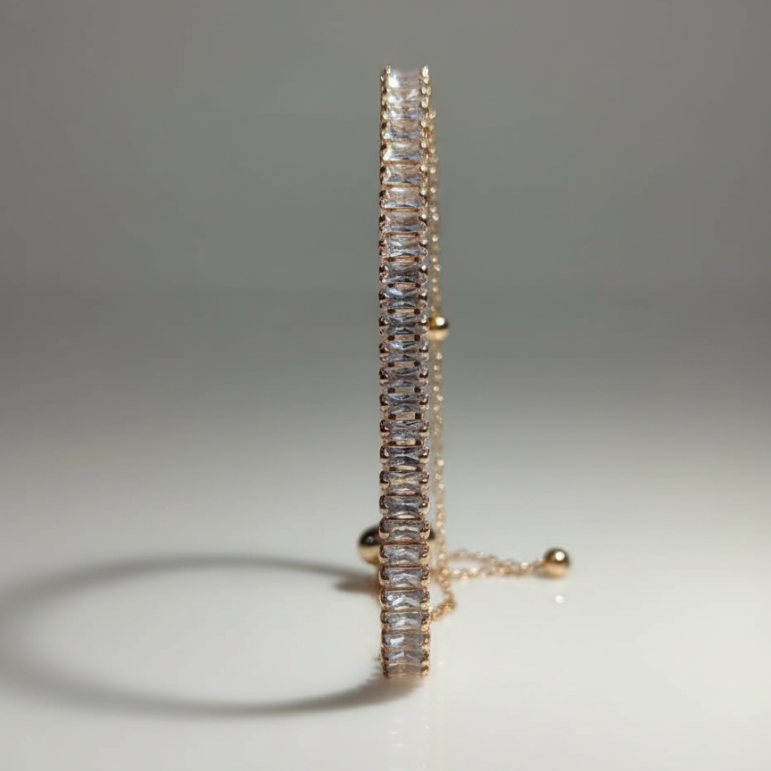 Gold bracelet with clear gemstones on a gray background